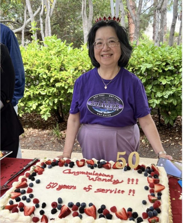 wendy leong in front of cake saying 50 years of service